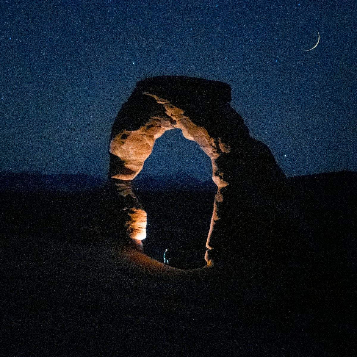 man in black jacket and pants standing on brown sand during night time